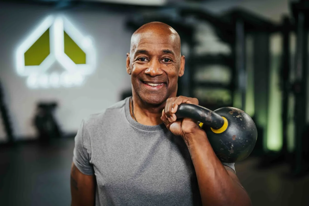 A member rests a kettlebell on his shoulder between sets at an Alloy studio