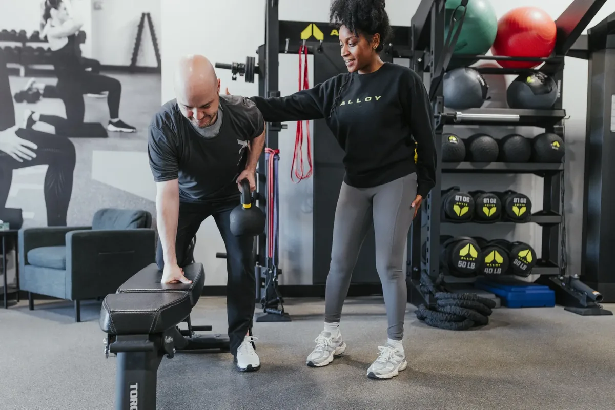 A coach guides a member through a single-arm kettlebell row during a session at an Alloy Personal Training studio
