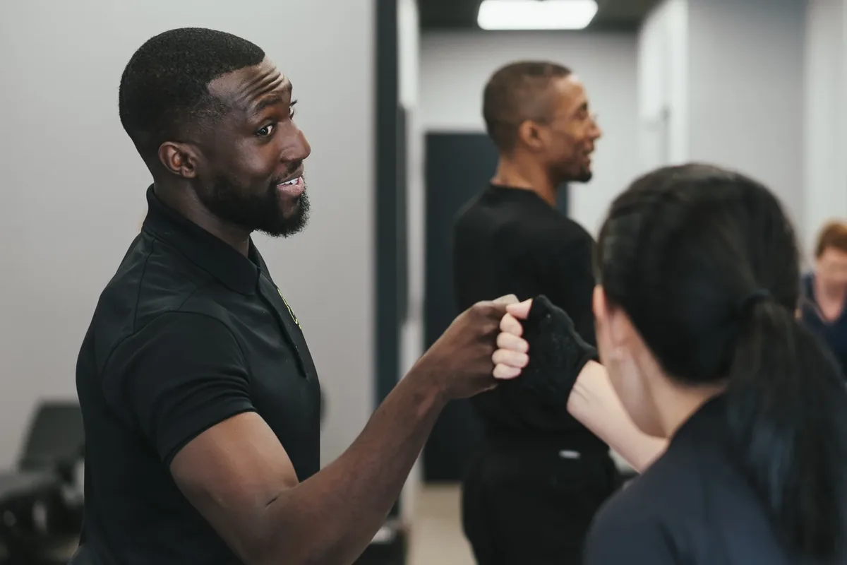 A coach greets members with a fist bump before a session at an Alloy Personal Training studio