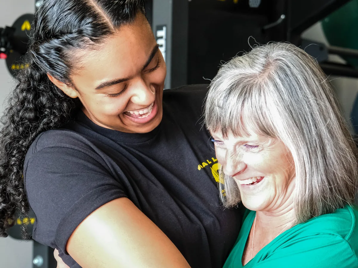 Coach Adila Gathers hugs a member at Alloy Personal Training Colorado Springs